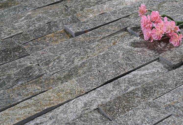 A worker repairing loose or broken stacked stone veneer on a wall